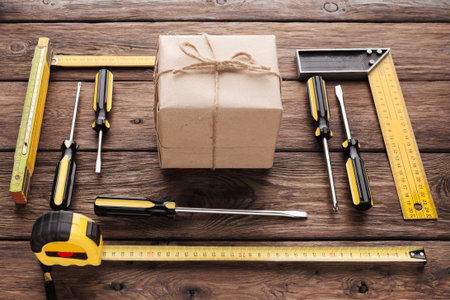 Tools Arranged Around a Wrapped Package on Wooden Surface for DIY Project Preparationの写真素材