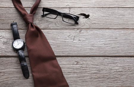 Watch, Tie, and Glasses Placed on Wooden Surface for Business Attire Preparationの写真素材