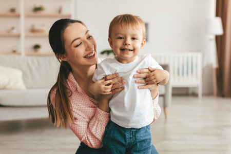 Happy maternity leave. Young mother looking at her toddler son with love and smiling, enjoying time...