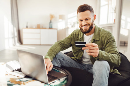 Male Buyer Using Laptop And Credit Card Shopping Online Indoorsの写真素材