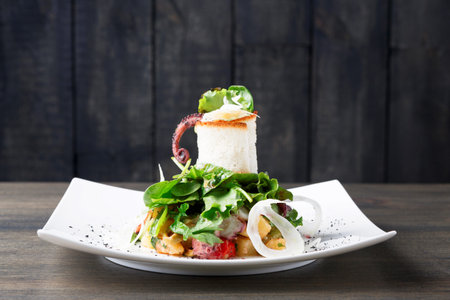 Delicious Seafood Salad Served on a White Plate With Fresh Greens and Tentacle Presentationの写真素材