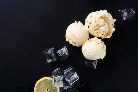 Lemon Ice Cream Served With Ice Cubes and Lemon Slice on Black Surface