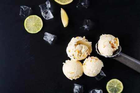 Ice Cream Scoops With Lemon Slices and Ice Cubes on a Dark Surface in a Kitchen Settingの写真素材