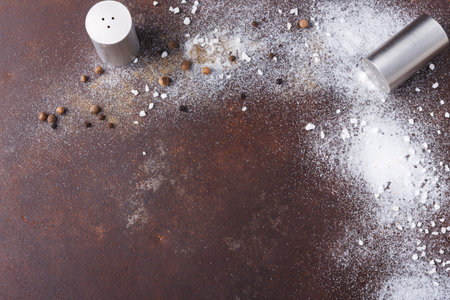 Spilled Salt and Pepper on a Brown Surface During Cooking or Meal Preparation in a Kitchenの写真素材