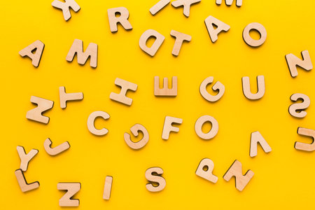 Wooden Letters Scattered on a Bright Yellow Background for Educational Use and Playの写真素材