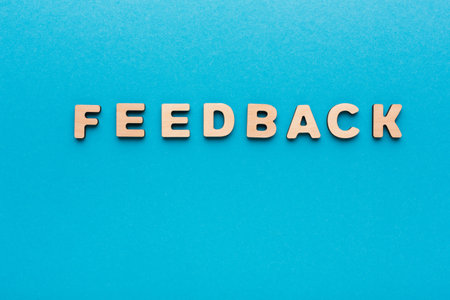 Various Wooden Letters Spell Feedback on a Blue Background for Feedback Collectionの写真素材
