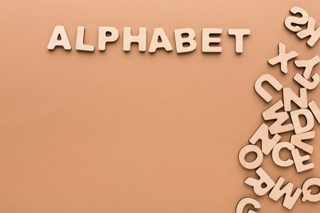 Wooden Letters Spell out the Word Alphabet on a Beige Background With Scattered Letters Nearbyの写真素材
