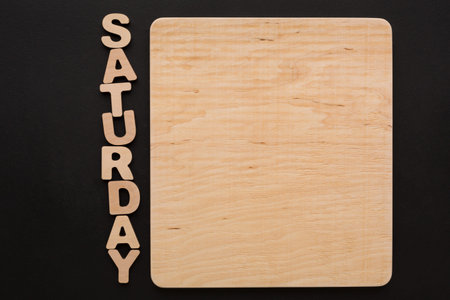 Wooden Board With Letters Spelling Saturday on a Black Backgroundの写真素材