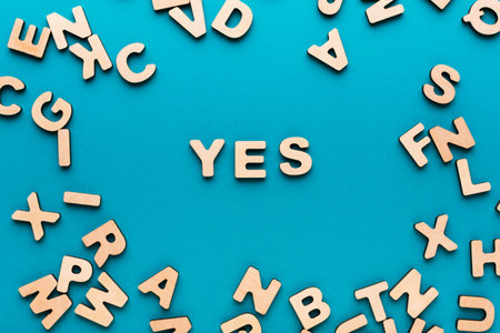 Wooden Letters on a Blue Background With the Word Yes in the Centerの写真素材