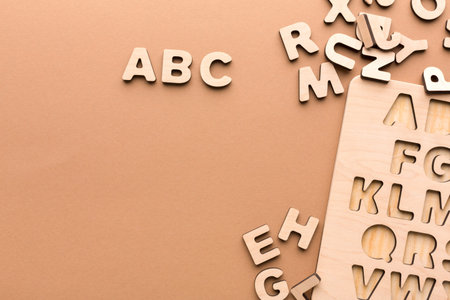 Wooden Letters Scattered on a Surface With Some Organized in a Board for Learning Activitiesの写真素材