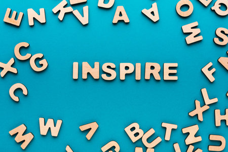 Various Letters Surround the Word Inspire on a Blue Background in a Creative Setupの写真素材