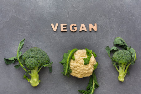 Green Vegetables With Word Vegan Arranged on a Gray Surface During Daylight Hours
