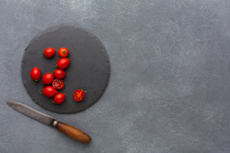 Fresh Cherry Tomatoes on a Slate Board With a Knife on a Gray Backgroundの写真素材