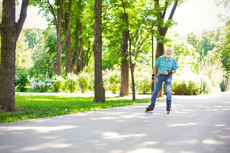 Older Man Skating on Rollerblades in a Park During Bright Sunny Dayの写真素材