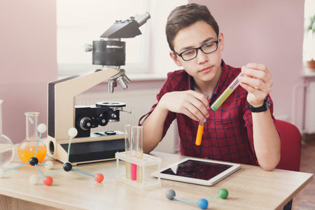 Young Student Conducts Science Experiment With Microscope and Test Tubes in Laboratory Setting