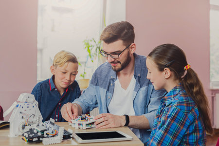 Kids Learn About Robotics With a Mentor During a Building Session in a Bright Room