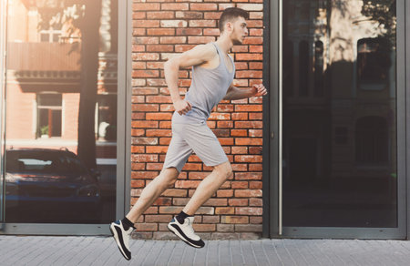 Man Runs Along a Brick Wall on a Sunny Day in an Urban Setting