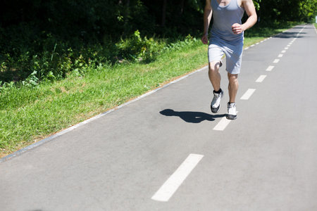 Person Runs on a Road Next to Grass in an Outdoor Setting During Daytime
