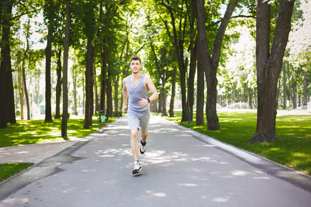 Young Man Jogging on a Path Surrounded by Trees in a Park During Daytime