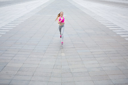 Woman Runs on a Wide Pavement Area During Daytime in a City