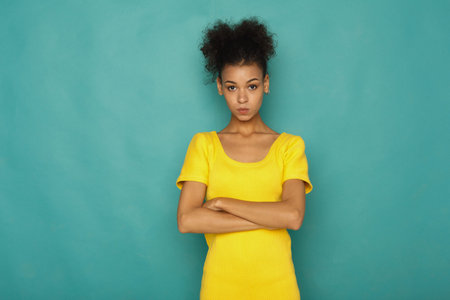 Young Woman Stands With Arms Crossed in Front of a Blue Background During a Photo Session