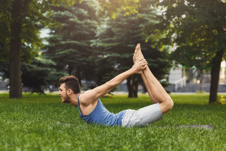 Man Practicing Yoga on a Mat in a Park During Daylight Hours