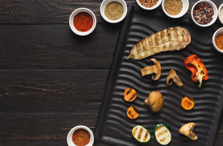 Collection of Grilled Vegetables and Spices on a Black Serving Tray in a Kitchen Setting
