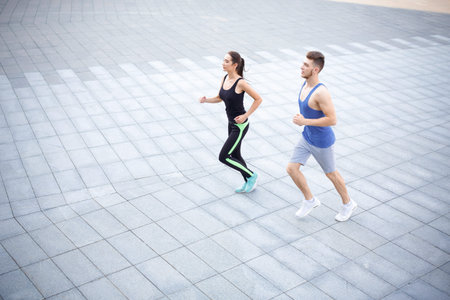 Running Couple Jogging on a Smooth Pathway During a Sunny Day in an Outdoor Setting