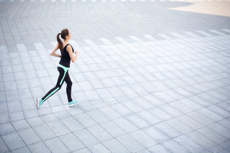 Woman Jogging on a Modern Pavement Area in an Outdoor Setting During Daylight Hours