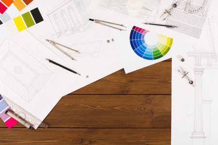 Collection of Architectural Design Sketches and Color Palettes on a Wooden Table