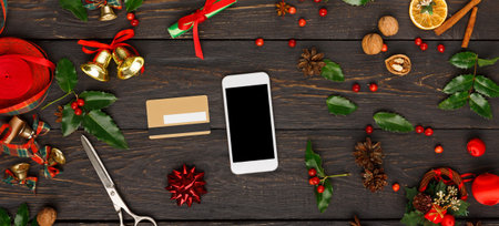 Collection of Holiday Decorations and Items Arranged Around a Smartphone on a Wooden Surface