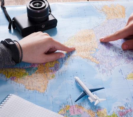 Planning a Trip With a Map, Camera, and Airplane Model on a Wooden Table