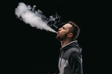 Man Exhales Large Cloud of Vapor While Standing in a Dark Room