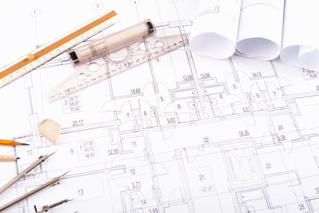 Blueprint Set Showing Designs for a Building With Tools and Rolls of Paper Displayed on a Table