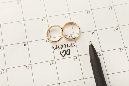 Calendar With Wedding Date Marked and Wedding Rings Placed on It for Planning