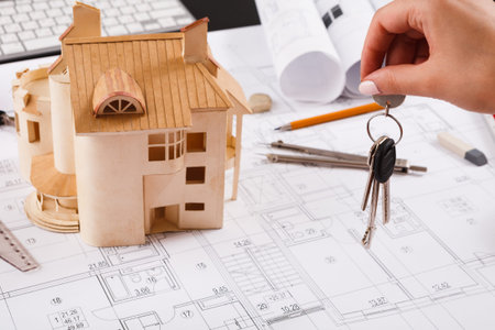 Collage of House Model and Keys on Construction Plans at Design Workspace