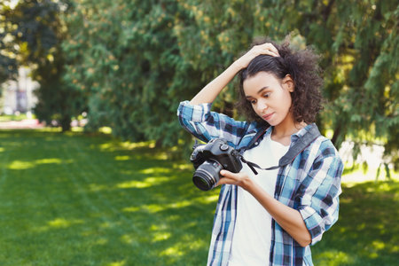 Young Woman Checks Camera Settings in a Green Park During a Sunny Day
