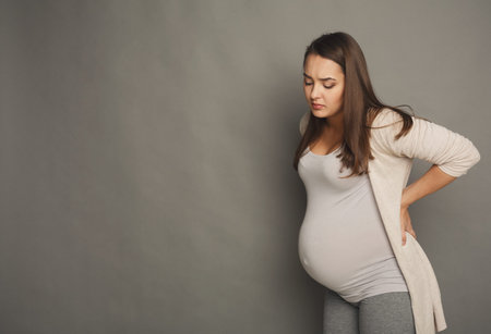 Pregnant Woman Views Her Belly in a Quiet Indoor Setting During the Eveningの写真素材