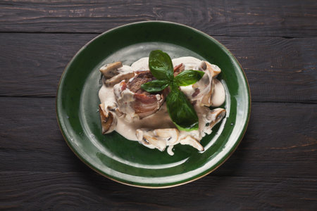 Delicious Food With Creamy Sauce Served on a Green Plate With Basil Leavesの写真素材