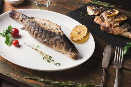 Collection of Grilled Fish Served on a Plate With Tomatoes and Herbs on a Wooden Table
