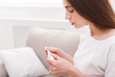 Woman Checking Health Status at Home With Thermometer During Afternoon Hours