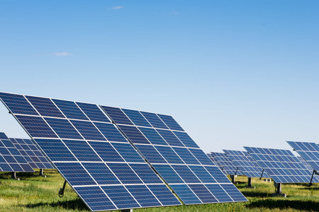 Solar Panels in a Large Field Under a Clear Sky on a Sunny Day Near a Rural Area