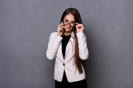 Young Woman Adjusting Glasses While Looking at the Camera in a Studio Setting