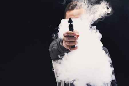 Man Exhaling Vapor From a Vape Pen Surrounded by Thick Clouds of Smoke Indoors
