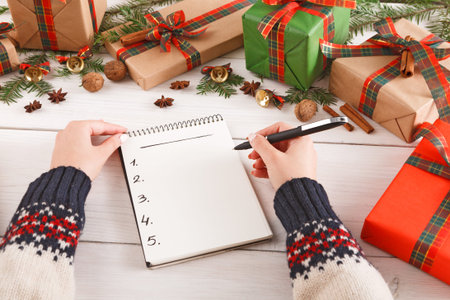 Making a Holiday Gift List With Presents and Decorations Around a Cozy Setting
