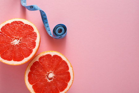 Grapefruit Halves With Measuring Tape on Pink Background at Kitchen Table