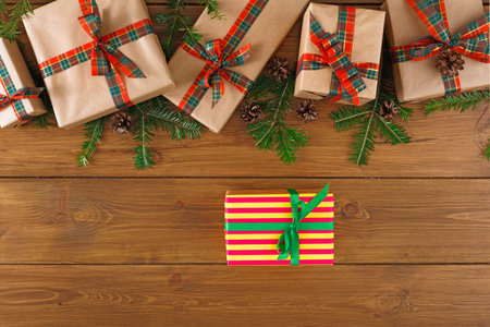 Collection of Wrapped Gifts Arranged on Wooden Surface With Green Branches and Pine Cones