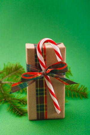 Gift Wrapped in Brown Paper With Red and White Candy Cane on Green Background