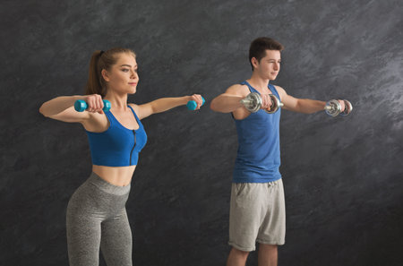 Fitness couple making exercise with dumbbells
