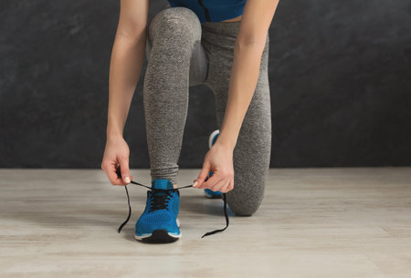 Woman tying up laces on sport shoes closeup